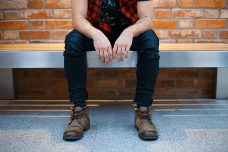 Young stylish guy sitting on the bench in a supermarket. Man waiting for his girlfriend.の写真素材