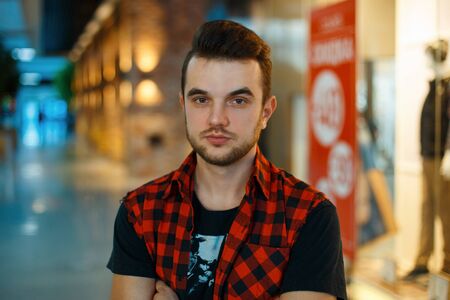 Young handsome guy in the red shirt on the background of a shopping center with a showcaseの写真素材