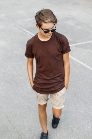 Fashionable young handsome boy in T-shirt and shorts walking on vacationsの写真素材