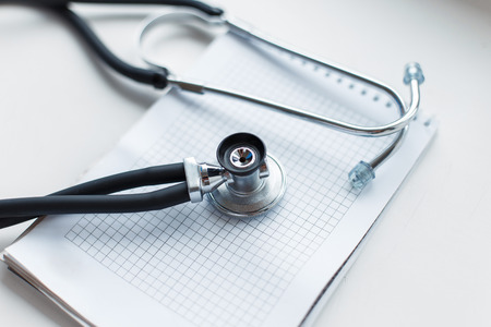 Medical phonendoscope with a notebook on a white background.の写真素材