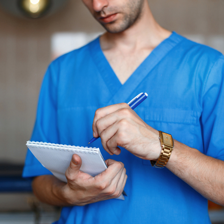 Doctor holding a pen and writes in a notebook.の写真素材