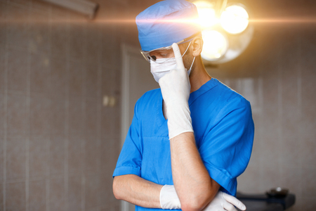 Doctor thinks in the operating room on the background of bright lights.の写真素材