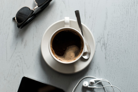 Coffee on the wooden table with the phone with headphones and sunglassesの写真素材