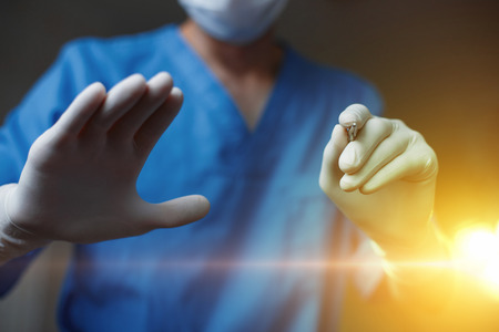 Surgeon makes plastic surgery on the background of the operating light. Scalpel in hand. The concept of modern beauty.の写真素材