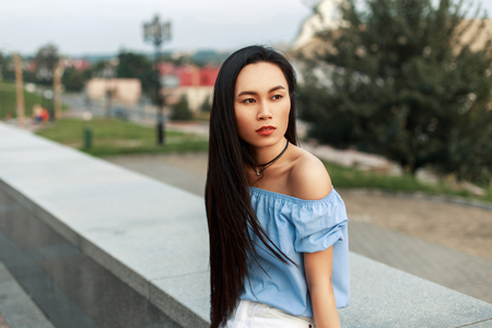 Beautiful young Asian woman with long hair resting in the parkの写真素材