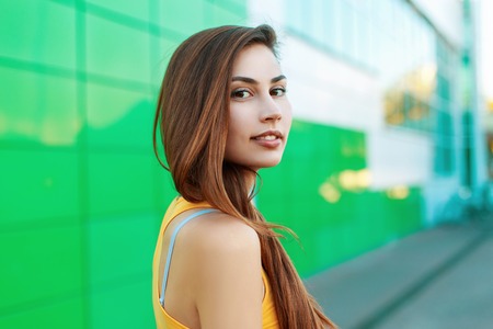Portrait of a beautiful girl in a yellow shirt on a green background.の写真素材