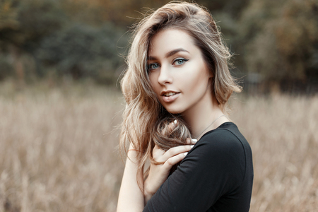 Portrait of a young woman in a black shirt on a background of nature
