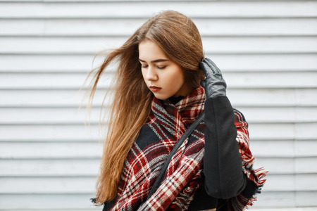 Beautiful young woman with a trendy vintage scarf near a wooden wall