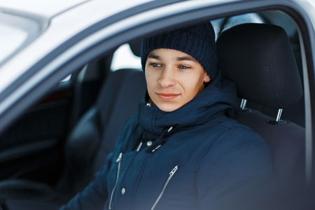 Young male in winter clothing sitting in a carの写真素材