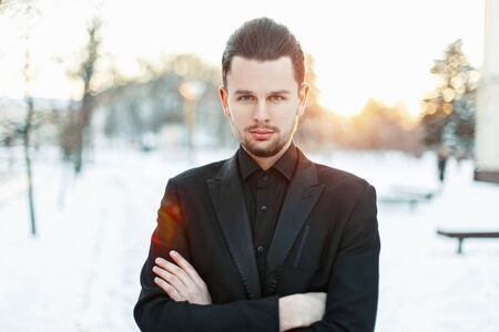 Handsome man in a black stylish suit on a sunset