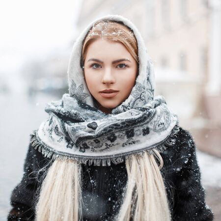 Beautiful young woman in a fashionable scarf on a winter dayの写真素材
