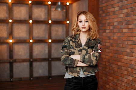 Young beautiful stylish woman in military jacket on a background of lightsの写真素材