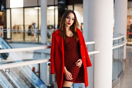 Stylish young woman in red coat at the mall