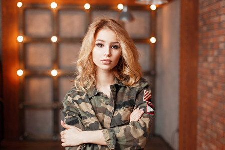 Young beautiful girl in fashionable military jacket on a background of lightsの写真素材