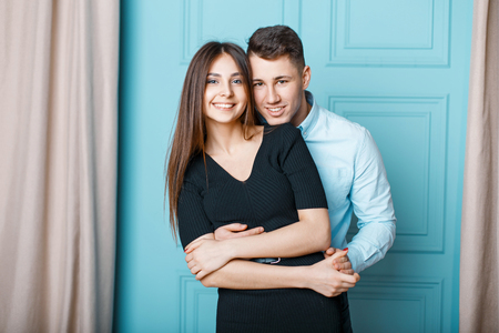 Beautiful cheerful young couple with smile in stylish clothes on vintage blue backgroundの写真素材