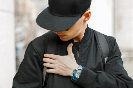 Fashionable man in a black baseball cap and black jacket in the cityの写真素材