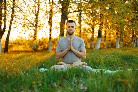 man with a beard practicing yoga on nature at sunset. Healthy lifestyleの写真素材
