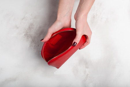 Girl holding a red vintage purse in hands on a white backgroundの写真素材
