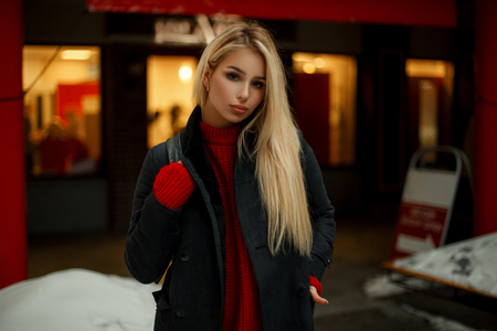 Beautiful young woman in trendy coat with bag walking near shop window and shoppingの写真素材