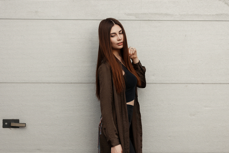 Beautiful young stylish woman in fashionable spring clothes near a metal gateの写真素材