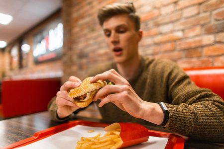 Lifestyle fast food. Hipster man holding a hamburger and going to eat it.の写真素材