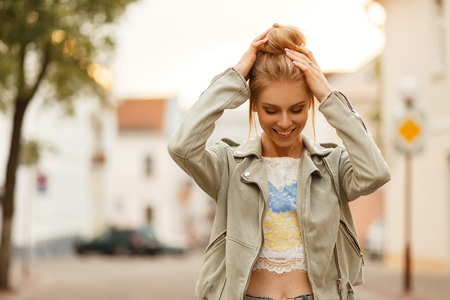 Beautiful young woman with a smile with a hairstyle in fashionable clothes walking outdoors on a summer dayの写真素材