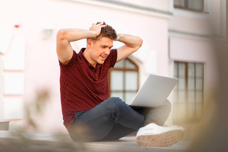 happy young businessman with a laptop enjoys the results of his work in the city. Concept of enjoy emotionsの写真素材