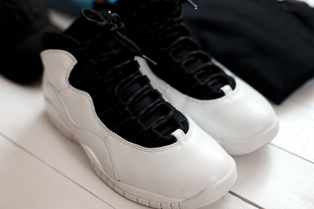 Stylish beautiful leather fashion sneakers with a T-shirt and jeans on a wooden table. Footwearの写真素材