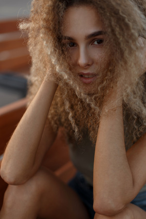 Fresh portrait of a beautiful young woman with curly hair outdoorsの写真素材