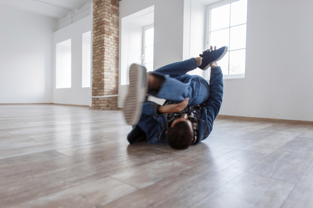 Young male dancer in fashionable denim dress dancing in studio on the floor