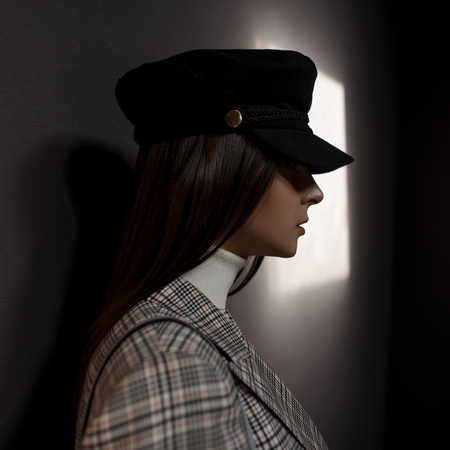Fashionable portrait of a beautiful stylish woman in a black hat and vintage fashion suit on a dark backgroundの写真素材