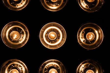 A group of electric bright orange vintage lamps on a black background. Close up