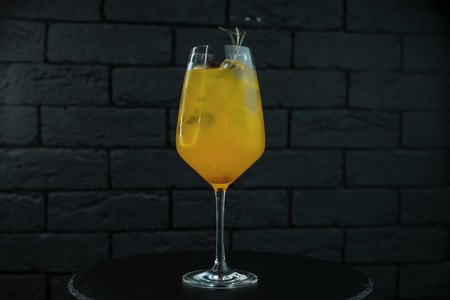 Fruit sweet alcoholic orange-yellow cocktail with ice cubes with orange juice and white rum on a table in a bar on a black backgroundの写真素材