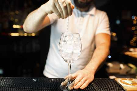 Bartender in white t-shirt at the bar or in a nightclub and makes an alcoholic cocktail. Lifestyleの写真素材