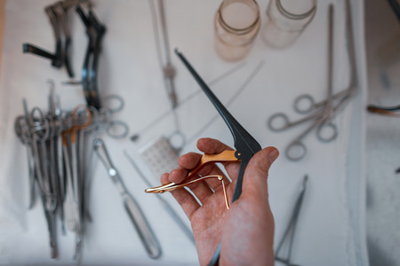 Doctor surgeon holds in his hand a black medical clip for performing an operation against the background of other metal instruments. Neurosurgeon and microsurgeryの写真素材