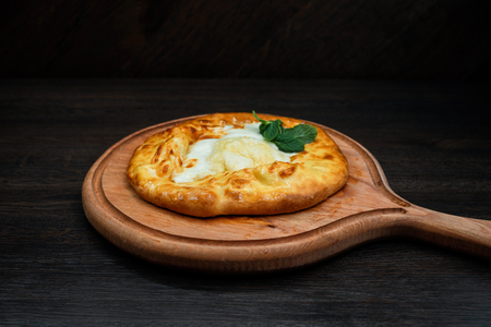 Adjara khachapuri with chicken egg on a wooden board in a restaurant. A popular Georgian national dish. Healthy food.の写真素材