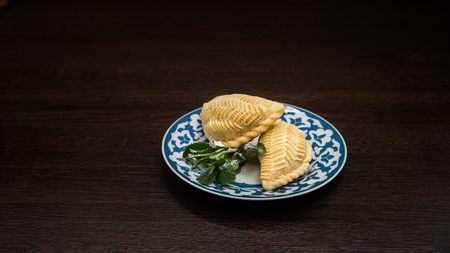 Delicious sweet Shekerbura decorated with mint leaves on a plate in a restaurant. Eastern sweets.