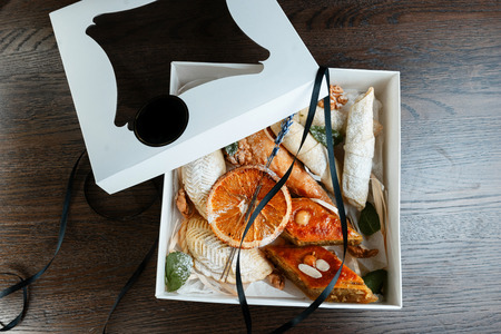 Oriental sweets in a vintage gift box decorated with lavender, black elegant ribbon, dried orange slices and mint leaves. Beautiful gift decoration. National Georgian cuisine. View from above.の写真素材