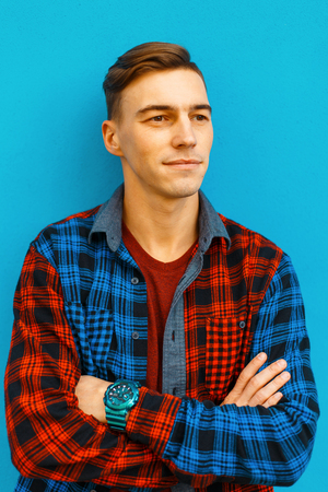 Cute happy young man with a stylish hairstyle in a stylish T-shirt in a fashionable checkered...