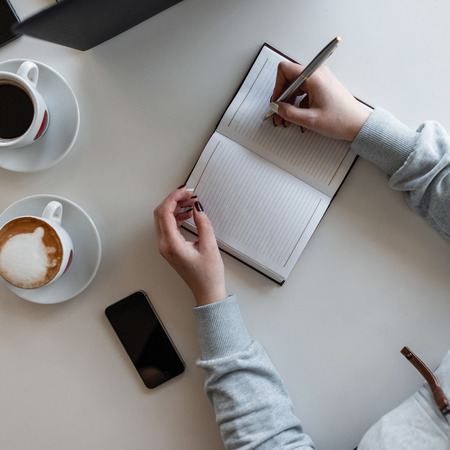 Woman manager sits at a white table at a business meeting in a modern office with a executive,...