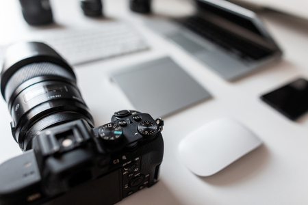 Workplace of a professional photographer. In the foreground is a black modern camera. Group of photo...