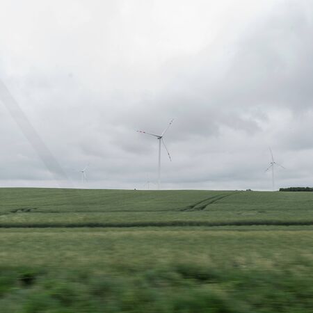 Modern windmill in a green field on a background a cloudy gray sky. Ecology and nature.