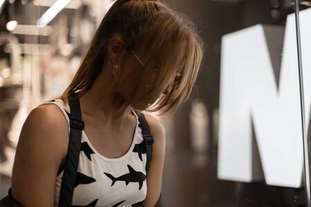Sexy young hipster woman with red hair in a fashionable white t-shirt with pattern in stylish...