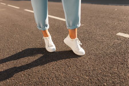 Stylish seasonal women's shoes. Closeup of female legs in blue elegant pants in leather white trendy...