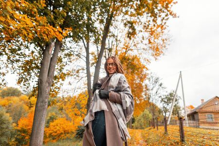 Fashionable happy young woman hipster in stylish glasses in trendy autumn outerwear with a vintage...