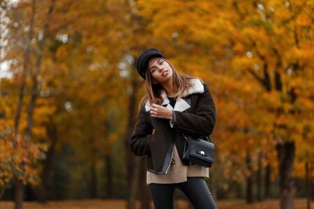 Pretty stylish model of a young woman in fashionable clothes in an elegant hat with a leather...