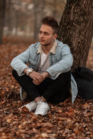 Young fashionable nice man with a stylish hairstyle with beard  in trendy clothing is resting...