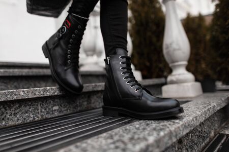 Fashionable young woman stands on the stone steps in the city in black trendy leather lace-up boots in vintage jeans. Close up of female legs in fashion autumn-spring shoes.New stylish shoe collectionの写真素材