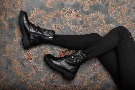 Top view on the legs of a young woman in vintage leather shoes in stylish black jeans in a room....
