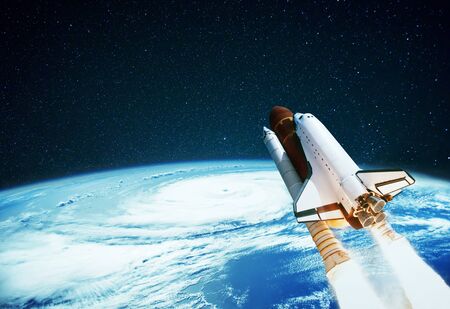 Space rocket launches into space on a background of planet Earth. Spaceship flies in the starry sky with a blue planetの写真素材